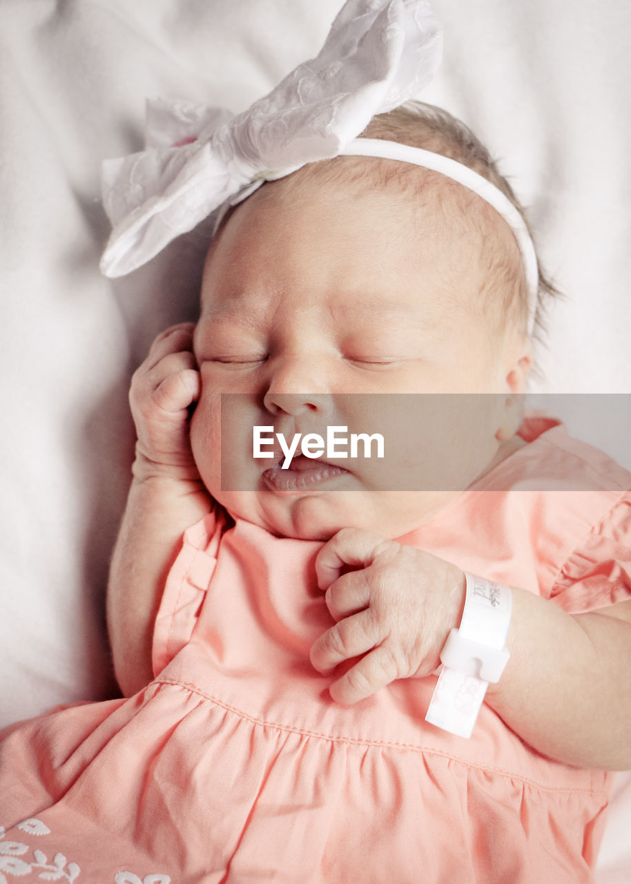 Close-up of cute baby girl sleeping on bed at home