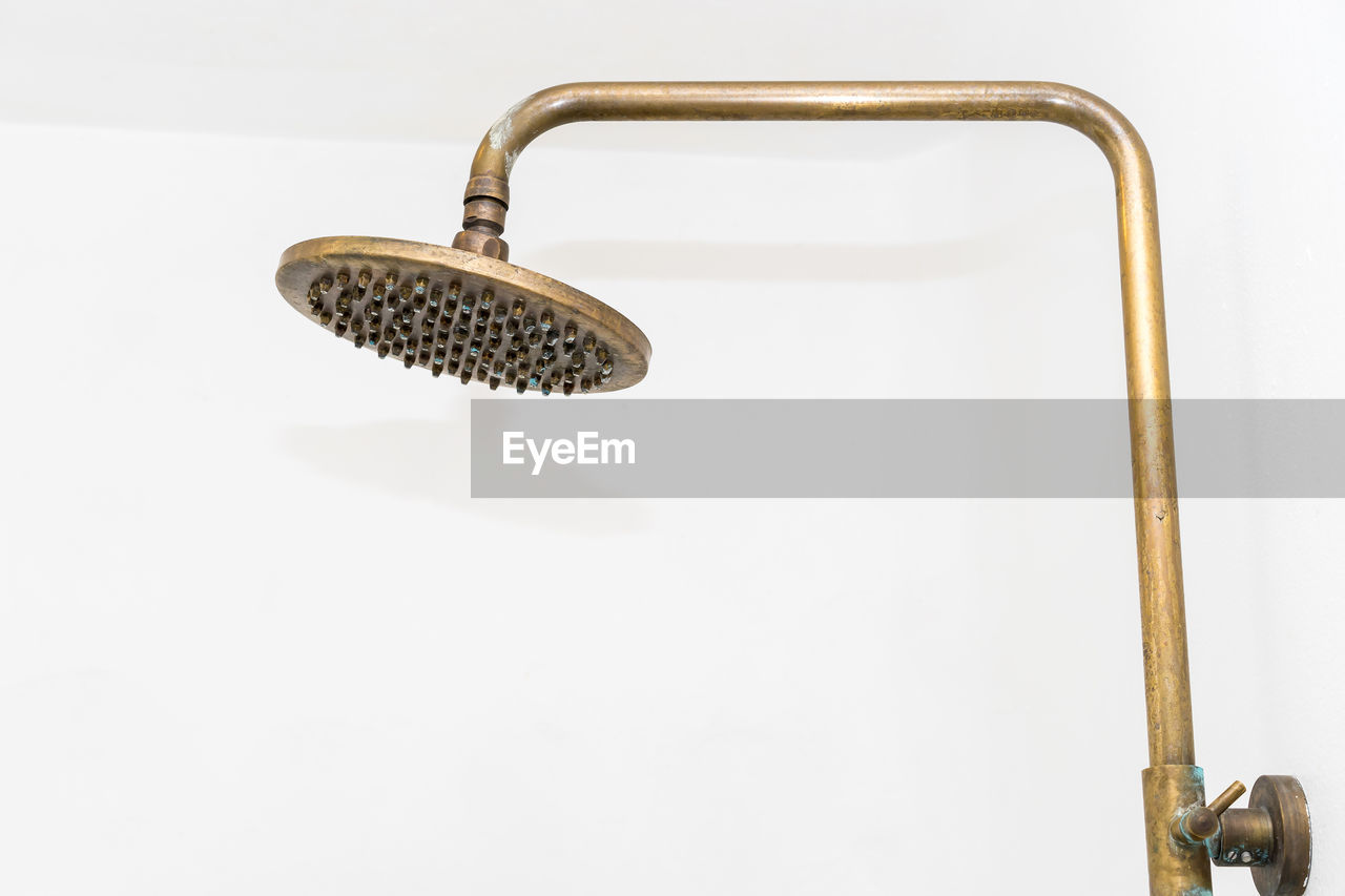 Close-up of shower head in bathroom against wall at home