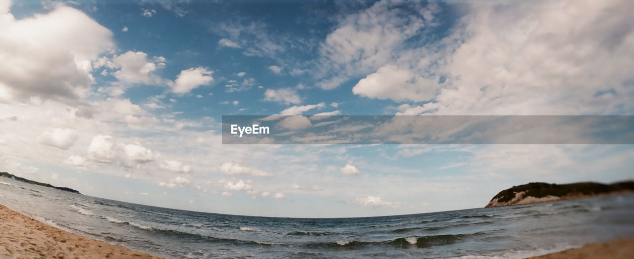 Fish-eye view of sea against cloudy sky