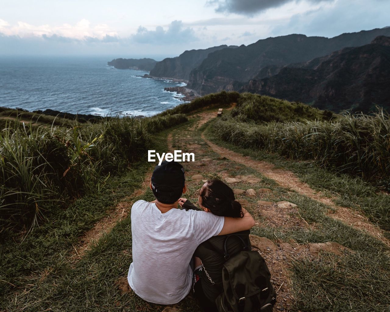 Rear view of couple on mountain looking at sea