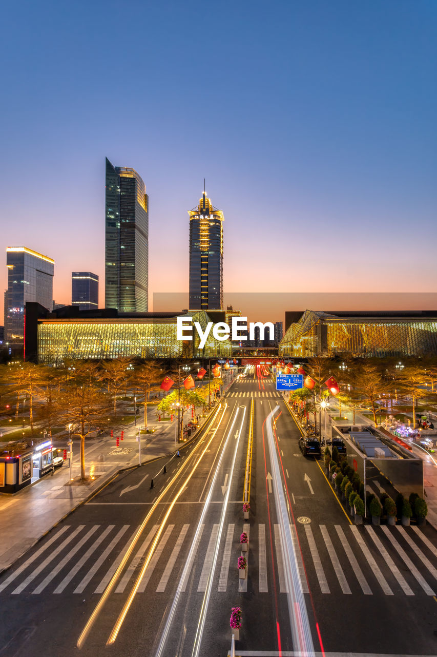 CITY STREET AND MODERN BUILDINGS AGAINST SKY DURING SUNRISE