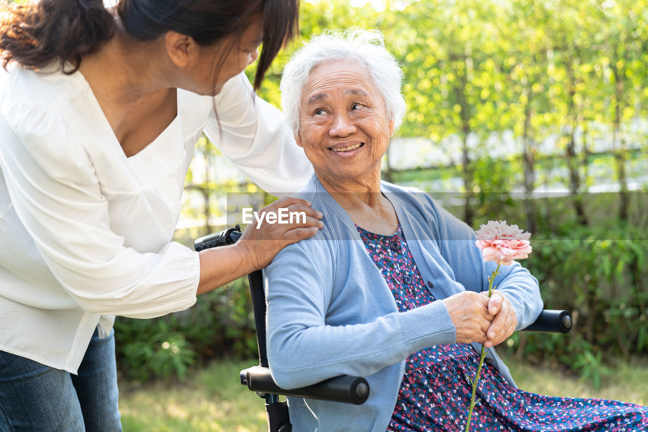 Asian senior or elderly old lady woman holding pink rose flower