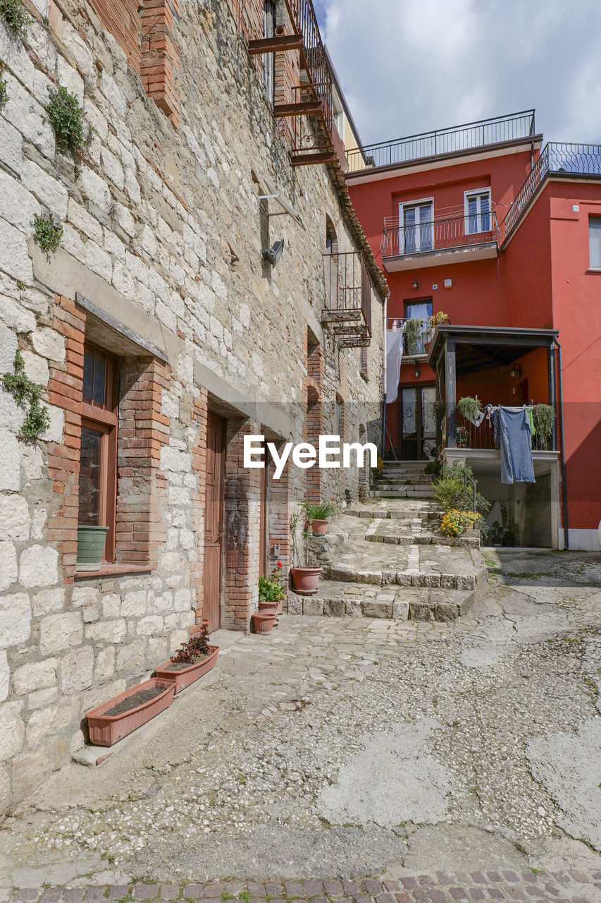 architecture, building exterior, built structure, town, building, neighbourhood, wall, village, city, street, cloud, house, residential district, residential area, sky, no people, nature, window, road, outdoors, old, facade, history, brick, alley, day, cottage, the past, travel destinations, wall - building feature, urban area, home