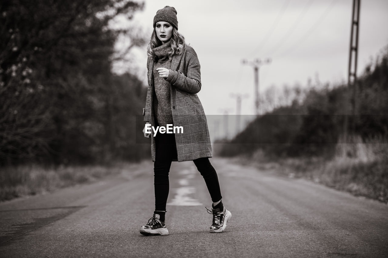 Full length portrait of woman standing on road