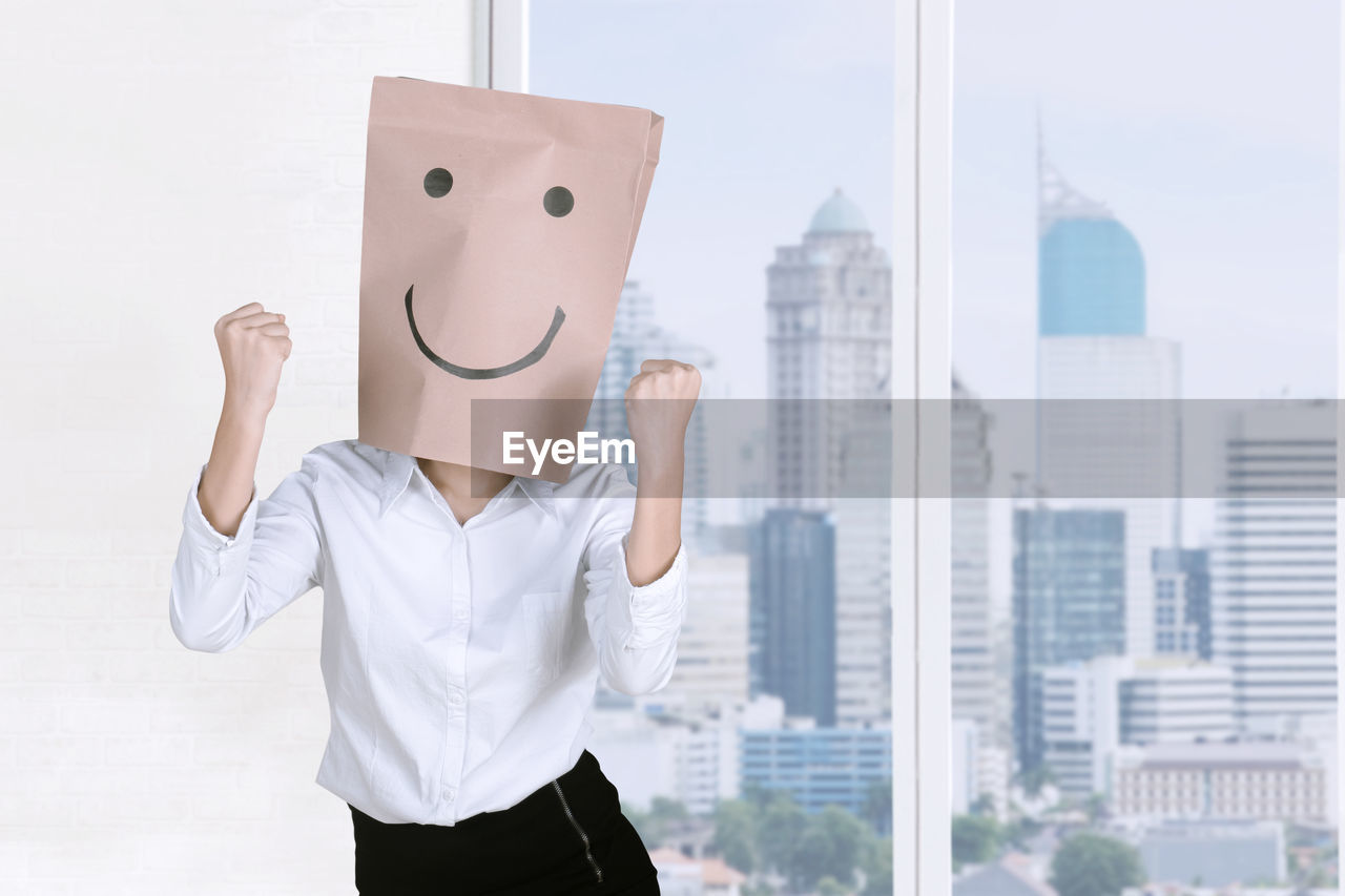 Businesswoman wearing paper bag with anthropomorphic face in office