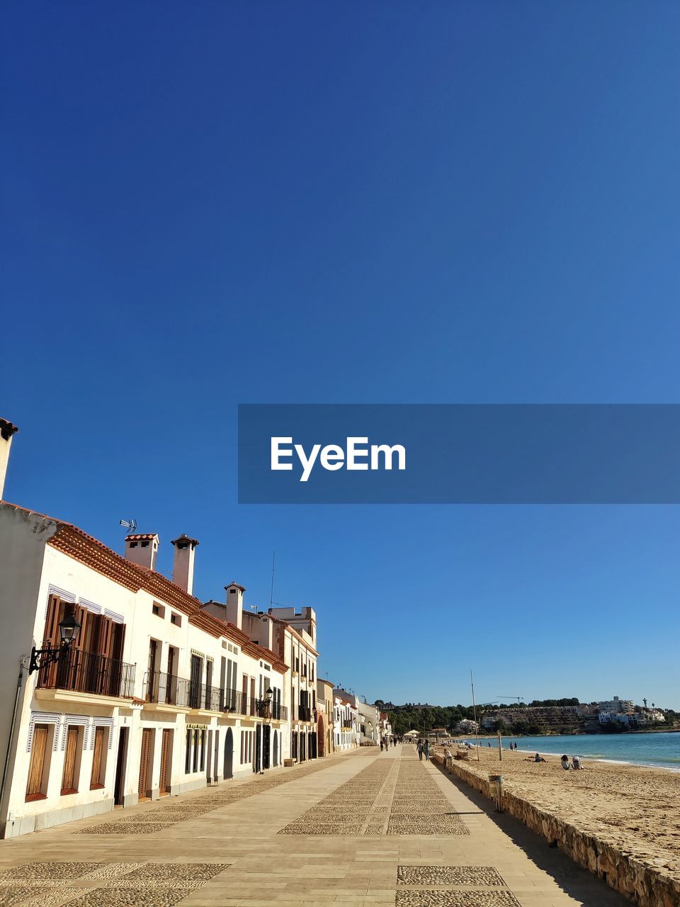 Street amidst buildings against clear blue sky