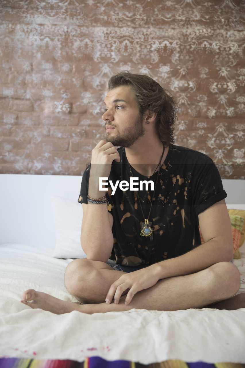 Young man sitting on his bed