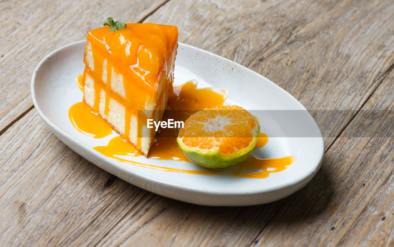 Orange cake with orange topping in wooden dish