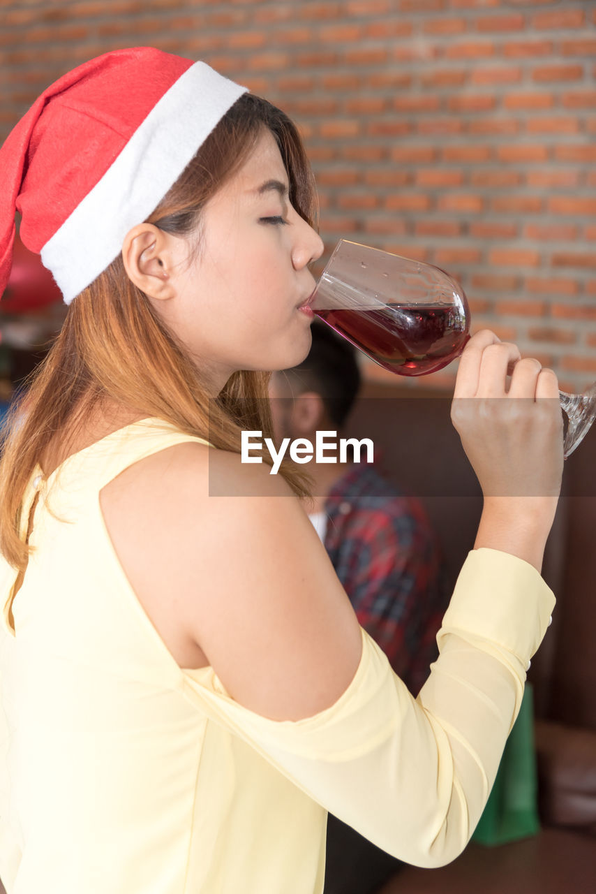 Young woman in santa hat drinking wine