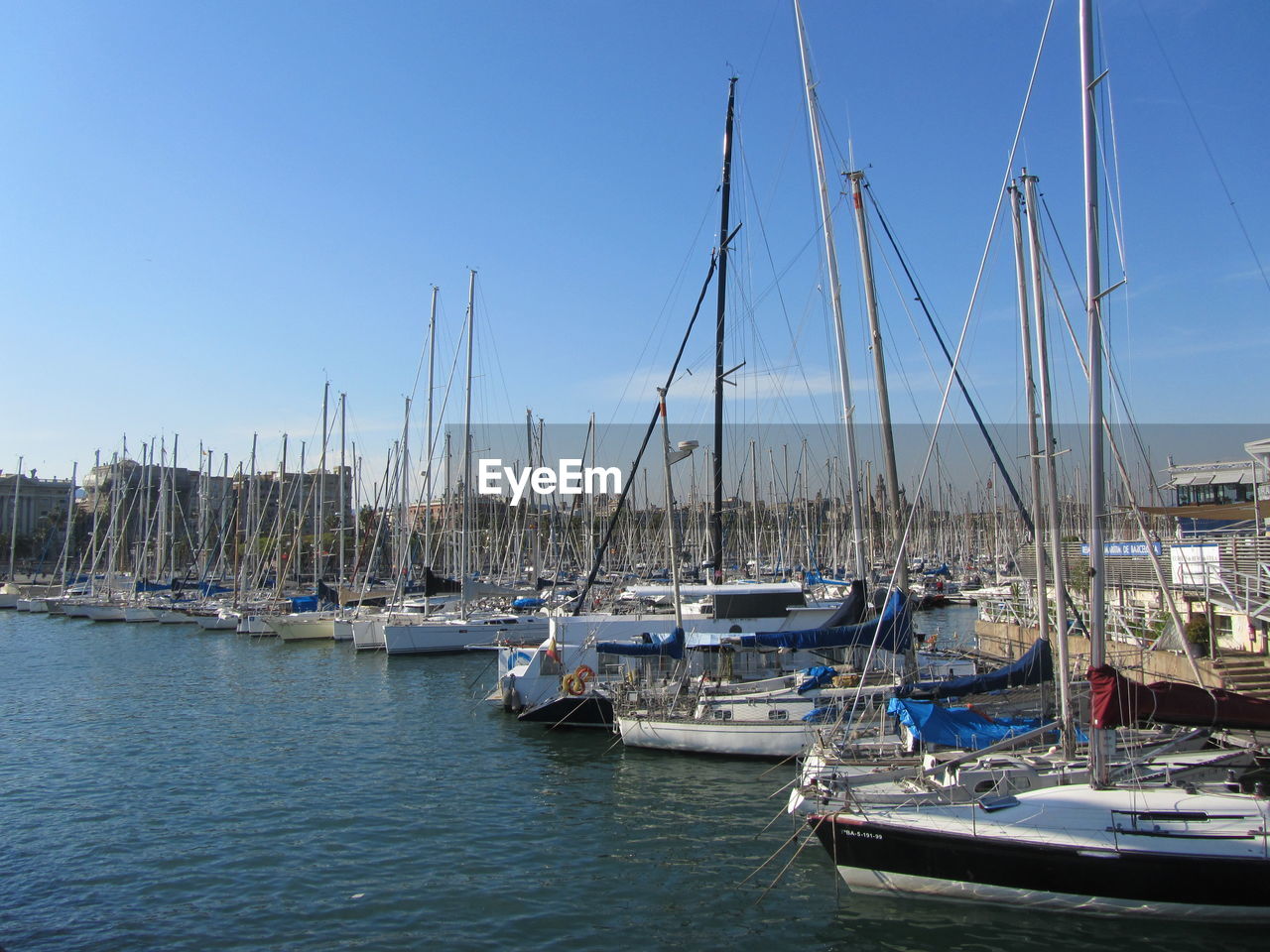 SAILBOATS MOORED ON HARBOR AGAINST CLEAR BLUE SKY