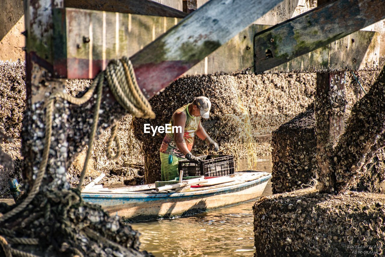 SIDE VIEW OF WOMAN IN BOAT AGAINST BUILT STRUCTURE