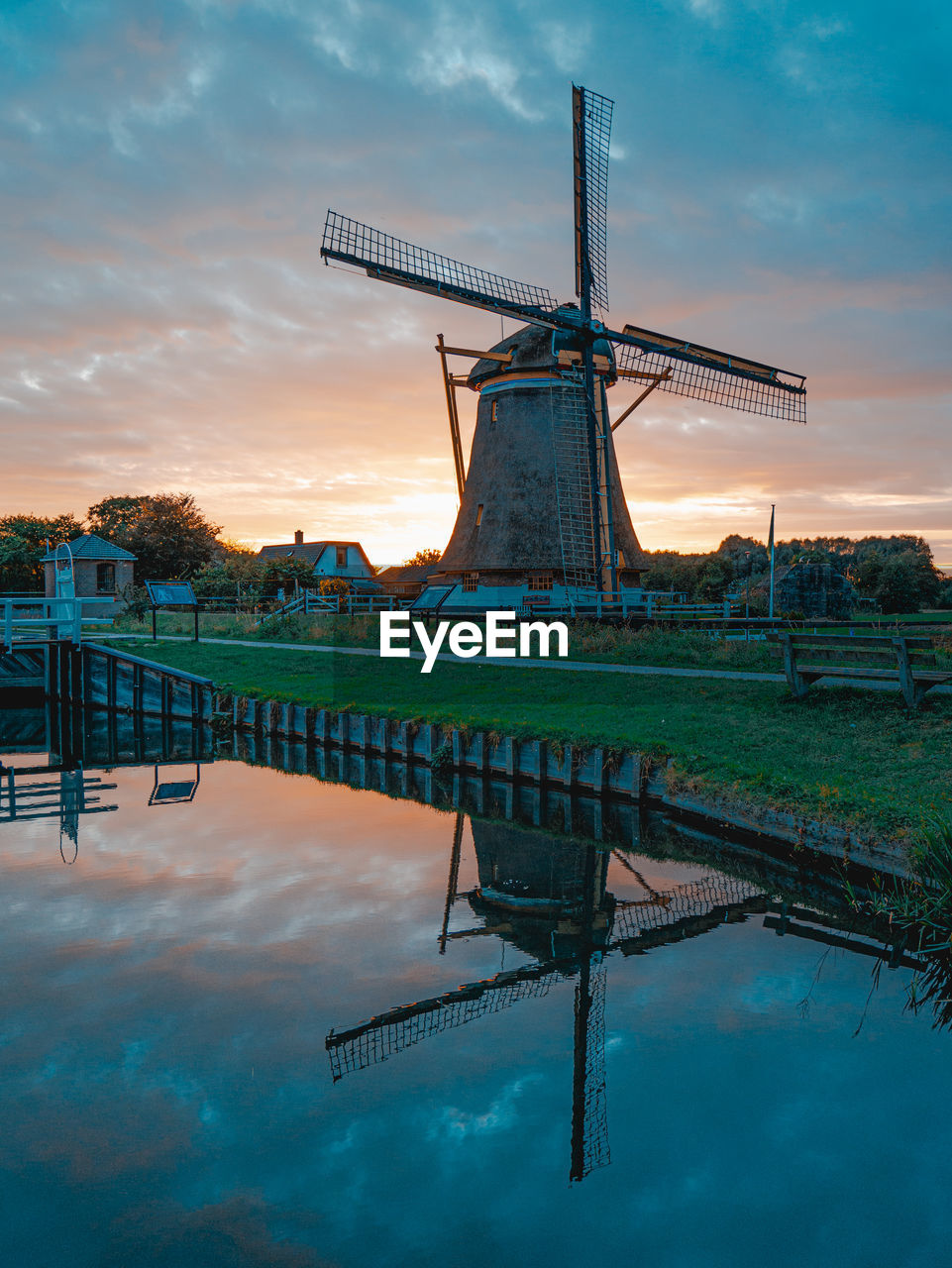 TRADITIONAL WINDMILL BY WATER AGAINST SKY