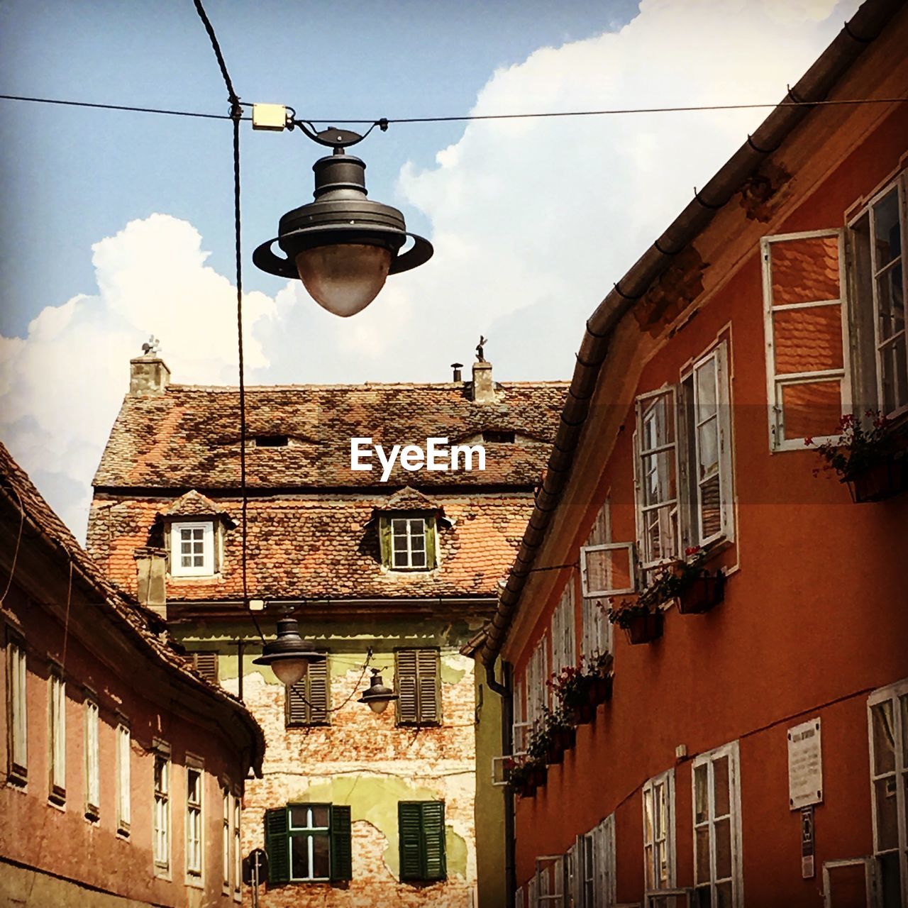 Low angle view of lamp by buildings against sky