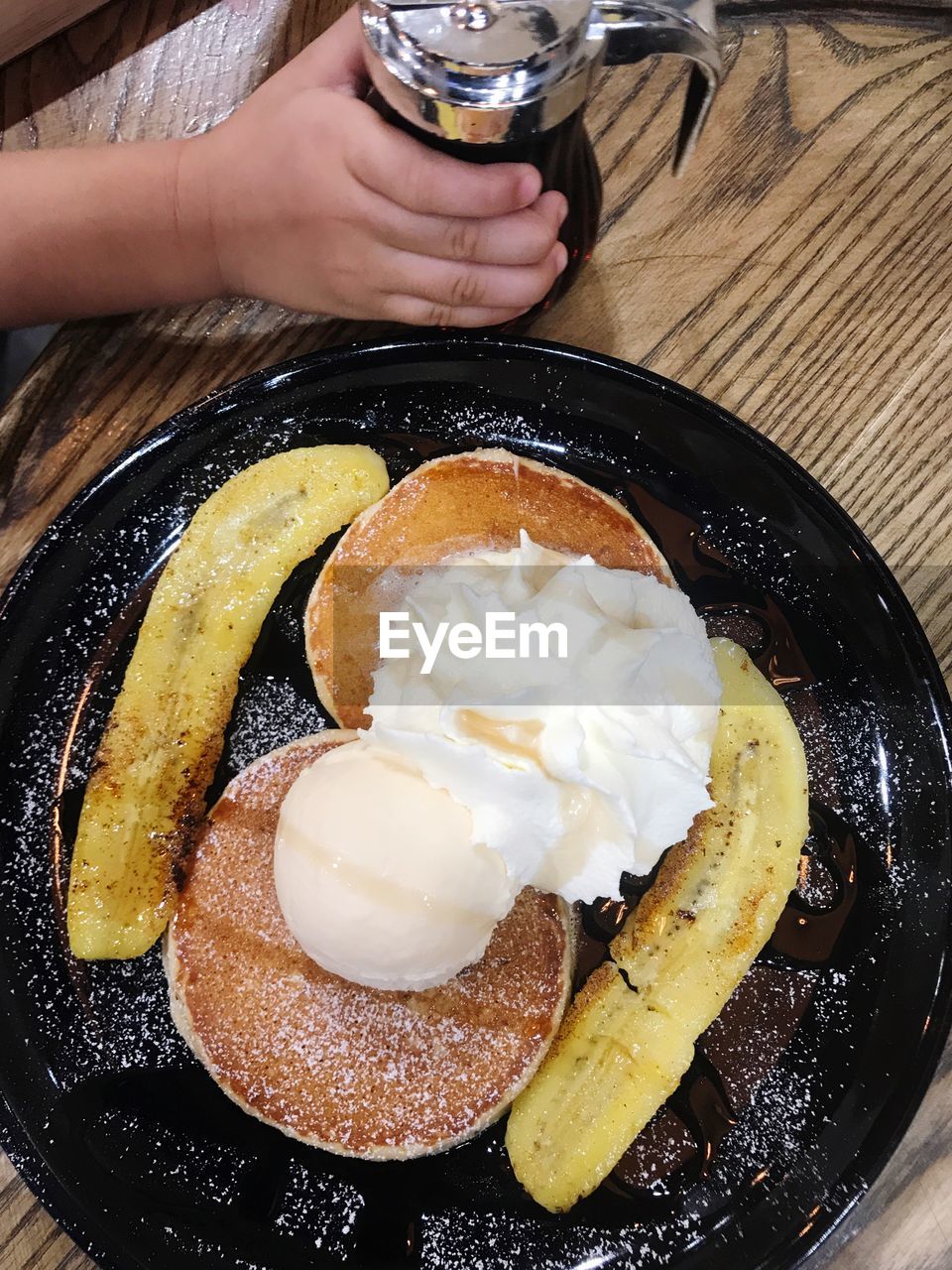 CLOSE-UP OF HAND HOLDING ICE CREAM IN PLATE