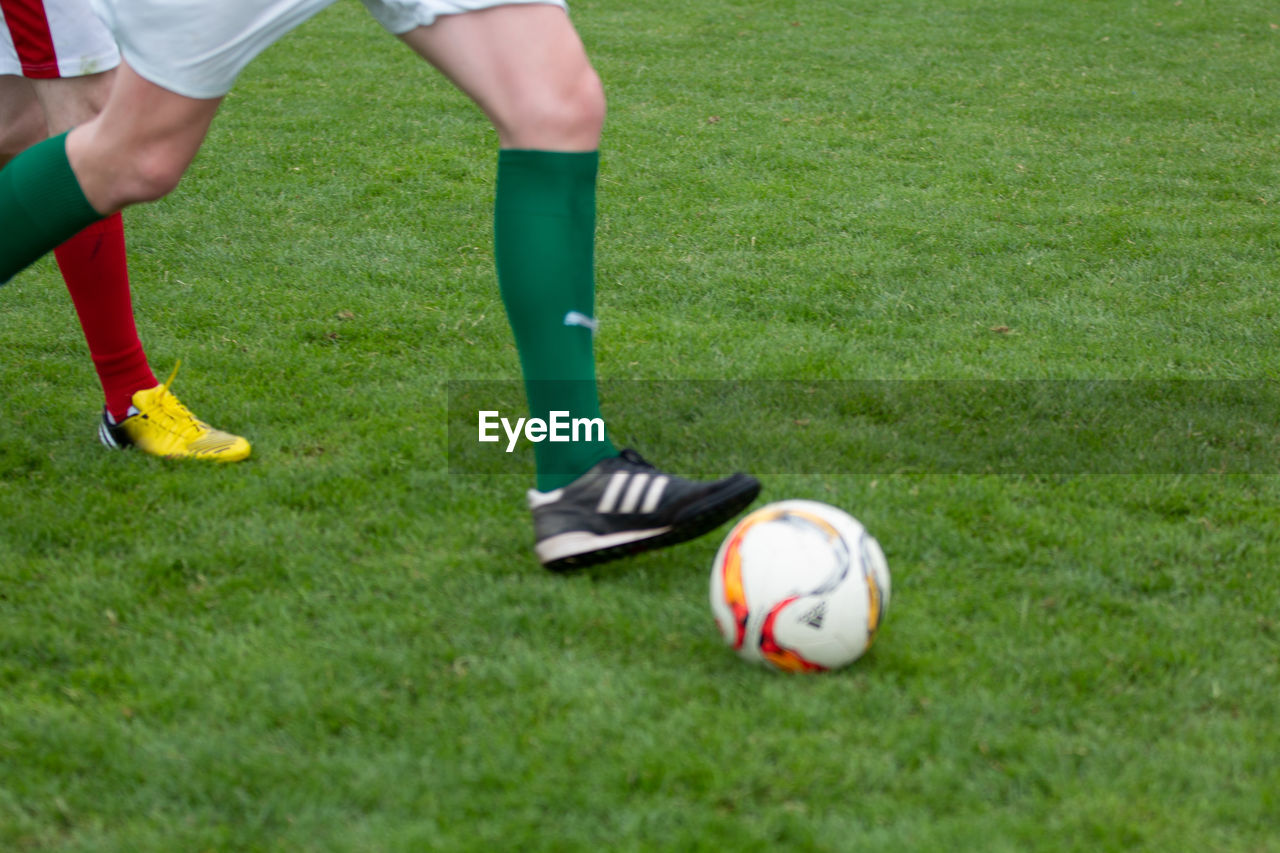 LOW SECTION OF MAN PLAYING SOCCER ON FIELD