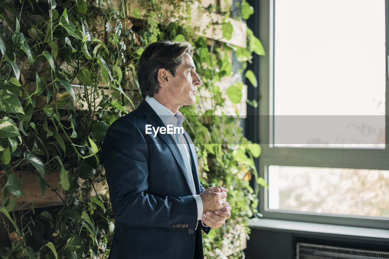 Businessman in green office looking out of window