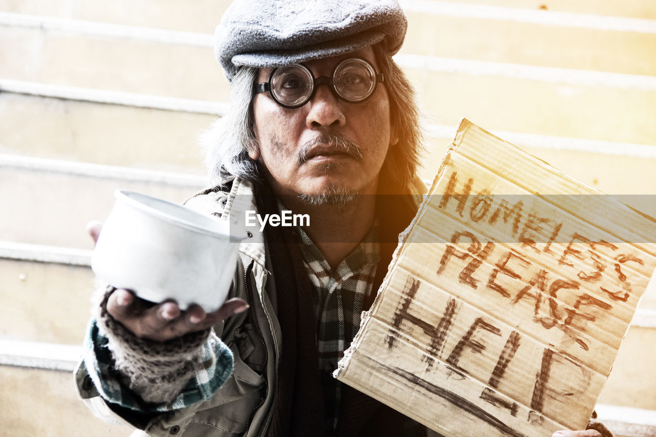 Portrait of beggar with text and bowl sitting on steps