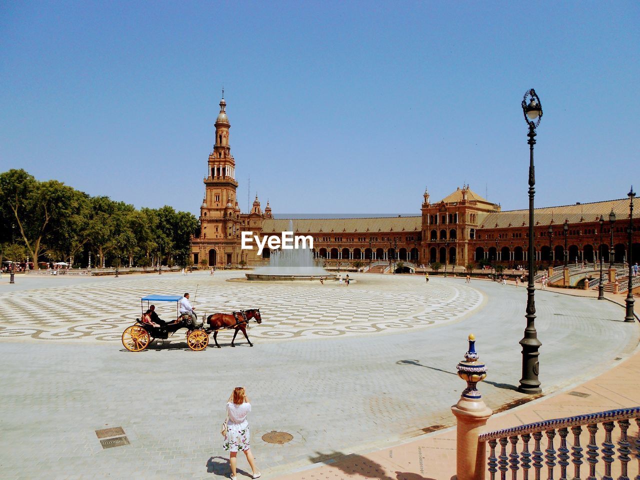 People walking on street by building against sky in city of sevilla 