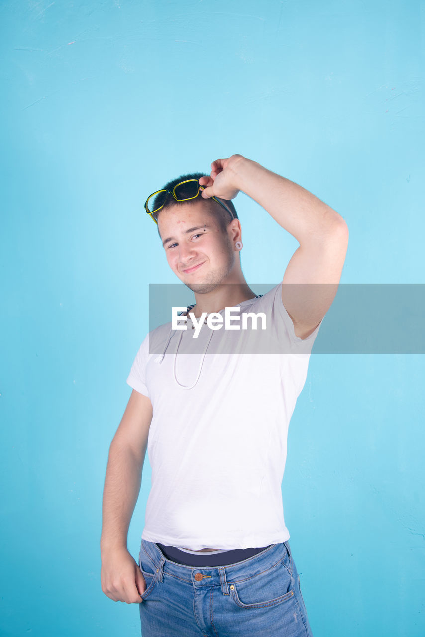 Portrait of smiling young man standing against blue background