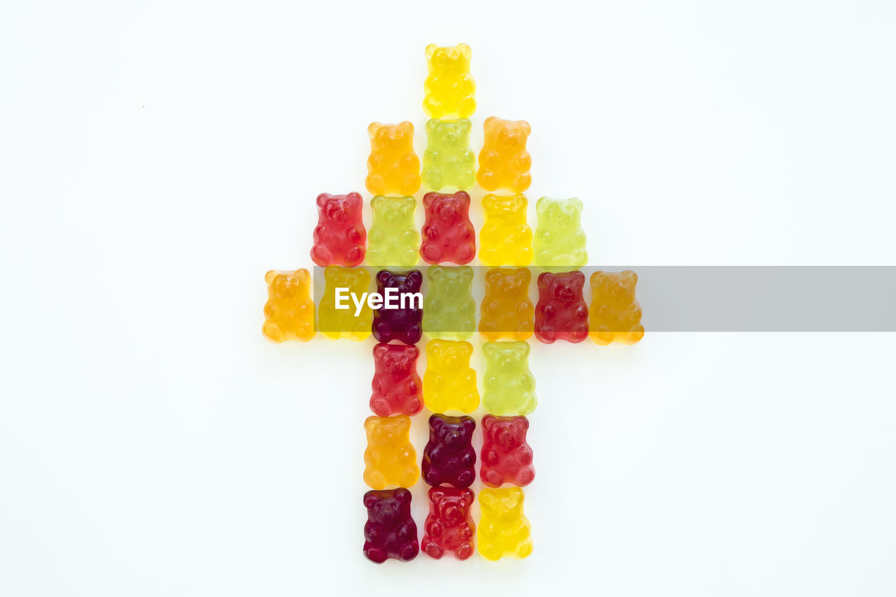 Close-up of arrow symbol made with gummi bears against white background