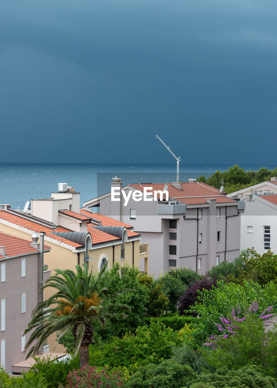 Buildings by sea against sky