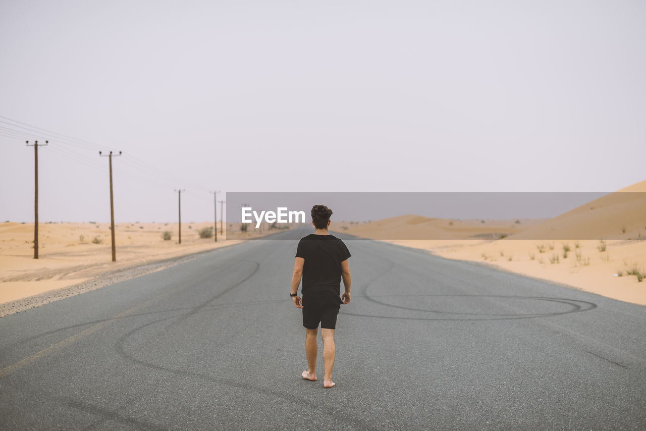 Rear view of man on road against clear sky