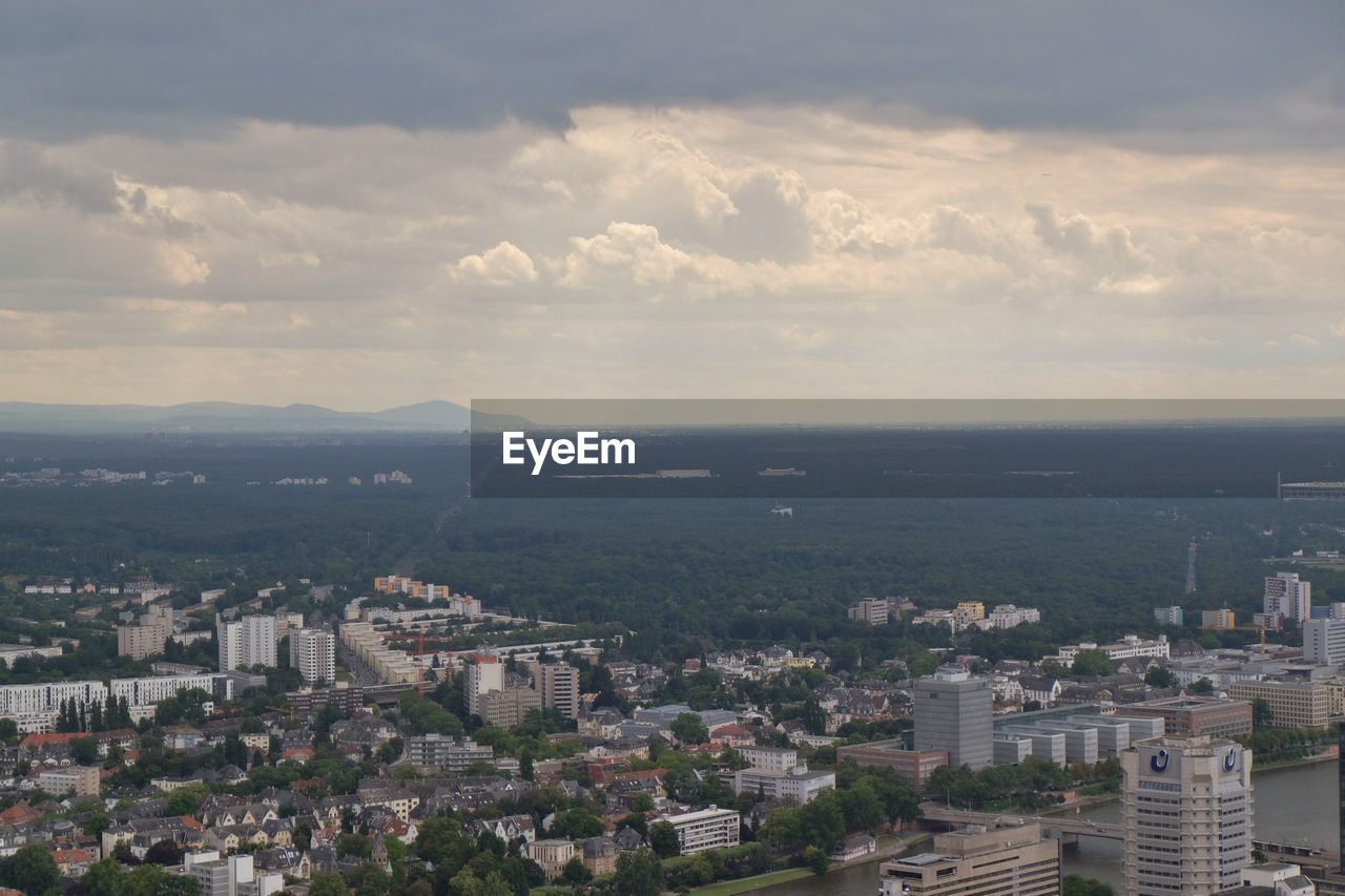 High angle view of cityscape by sea against cloudy sky