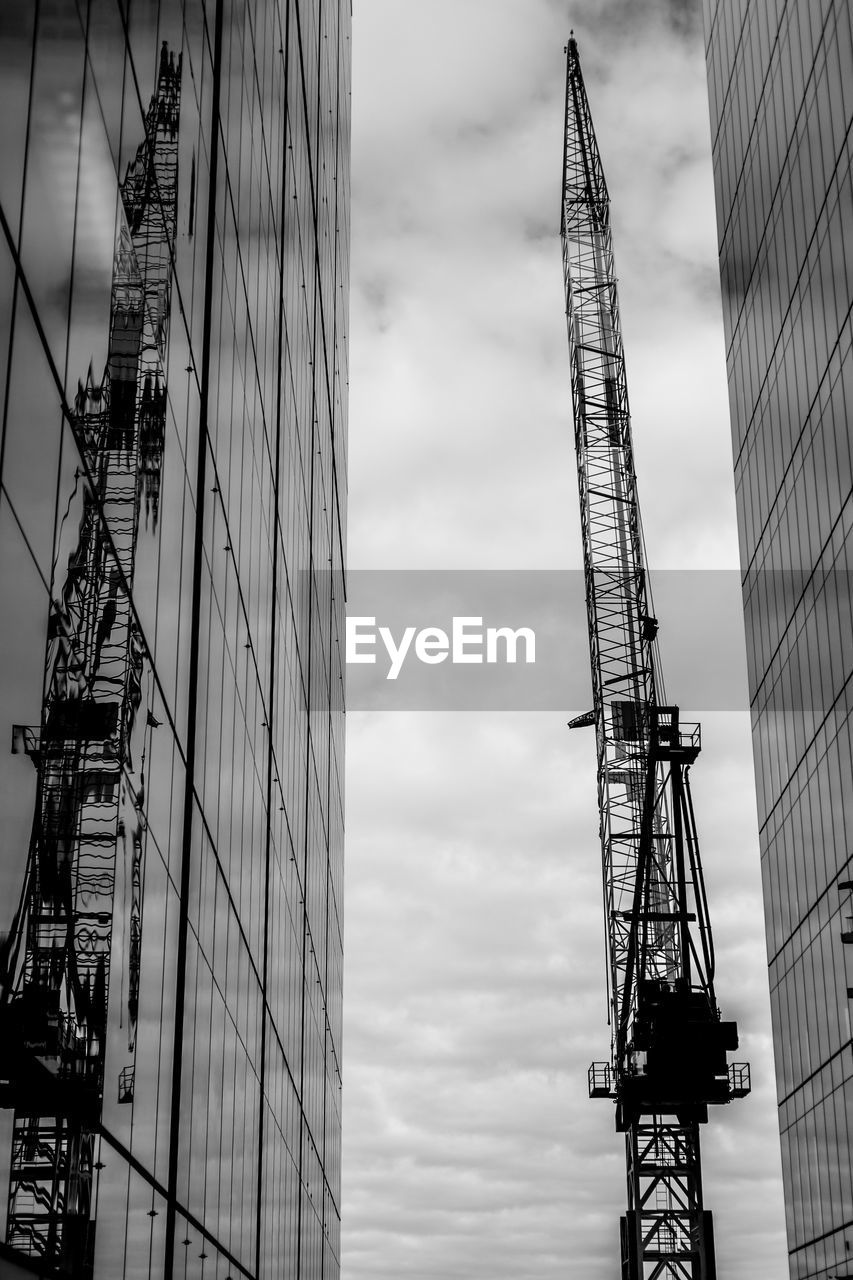 LOW ANGLE VIEW OF CRANE AGAINST SKY IN CITY