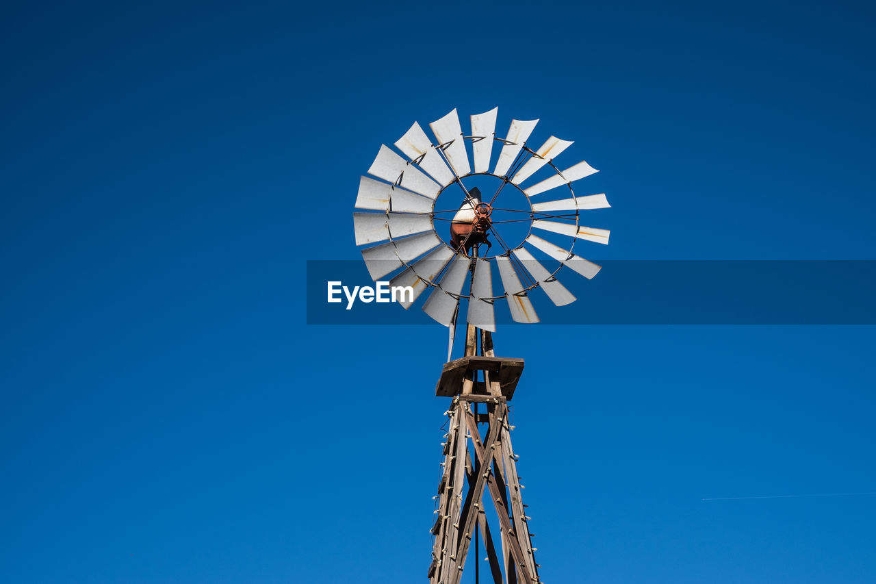 Low angle view of windmill against clear blue sky