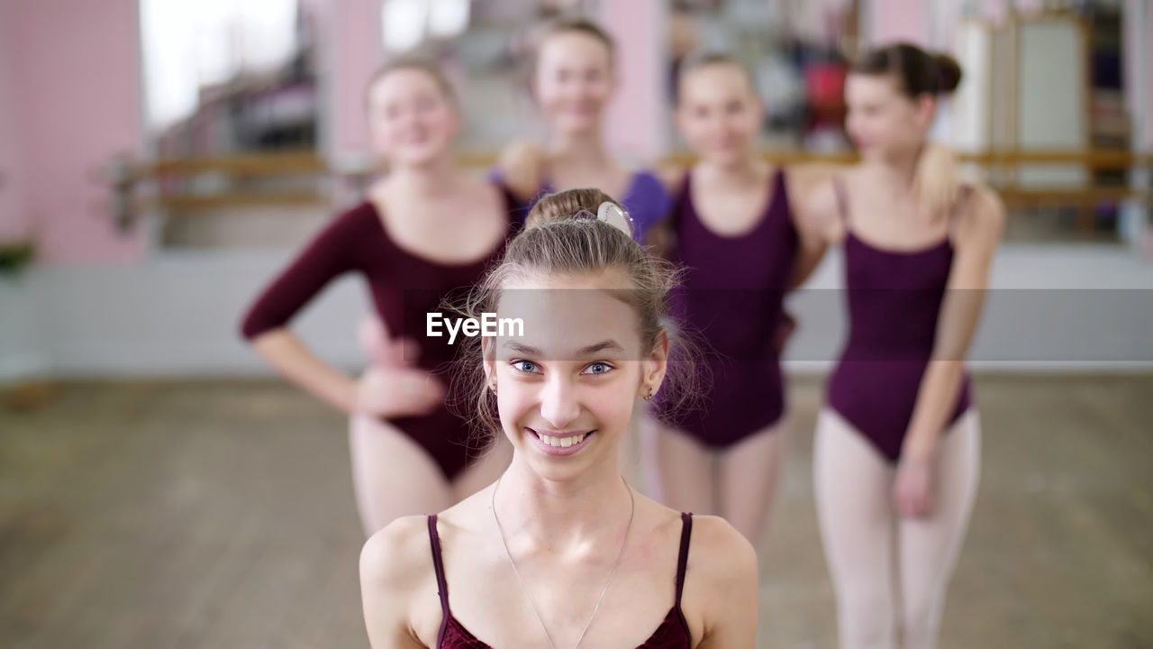 Portrait of a young girl ballet dancer in a lilac ballet leotard, smiling, sending an air kiss