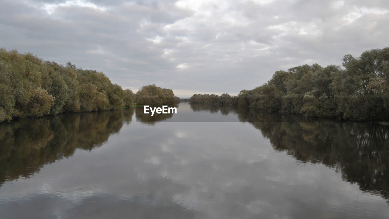 REFLECTION OF TREES AND SKY ON LAKE