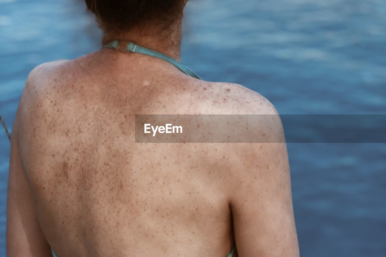 REAR VIEW OF SHIRTLESS MAN IN WATER