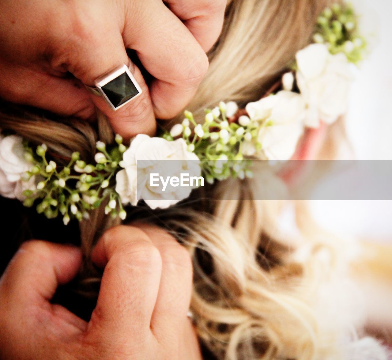 Cropped image of woman hands arranging floral crown in bride hair during wedding