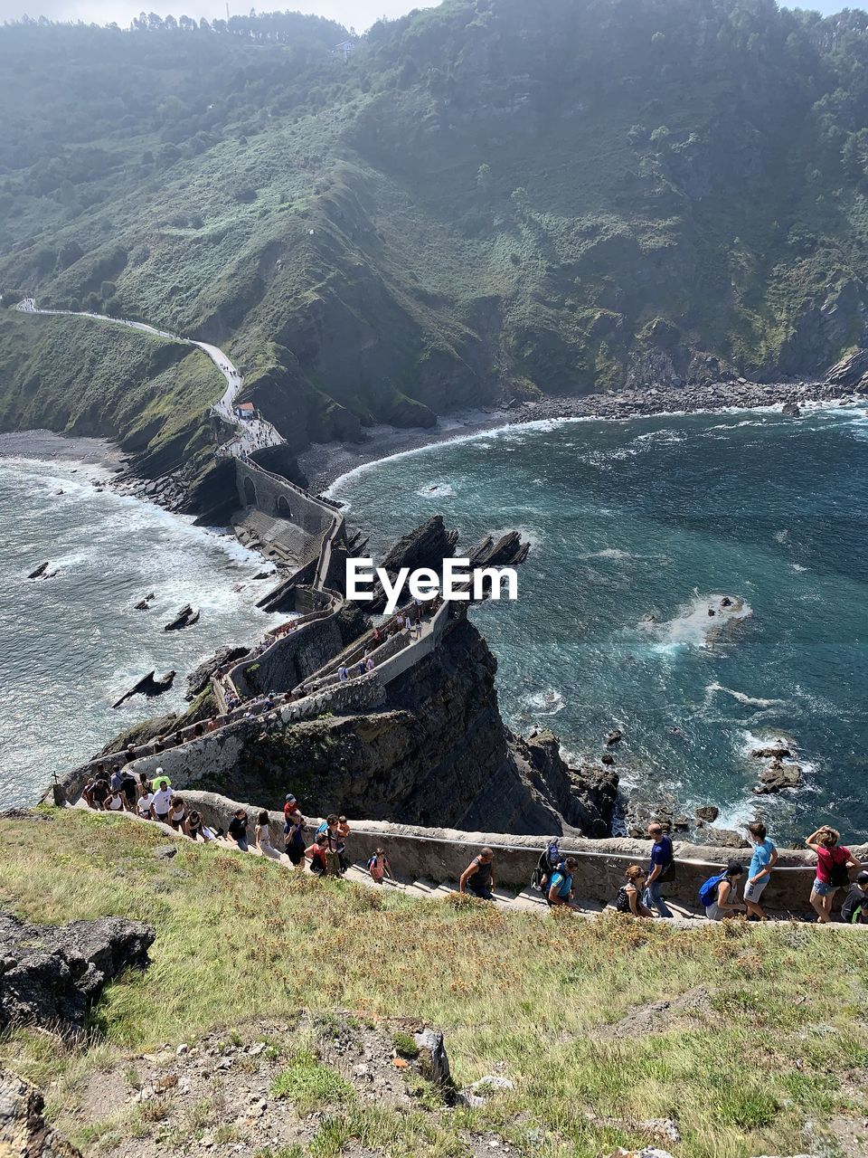 HIGH ANGLE VIEW OF PEOPLE ON SEA BY MOUNTAINS