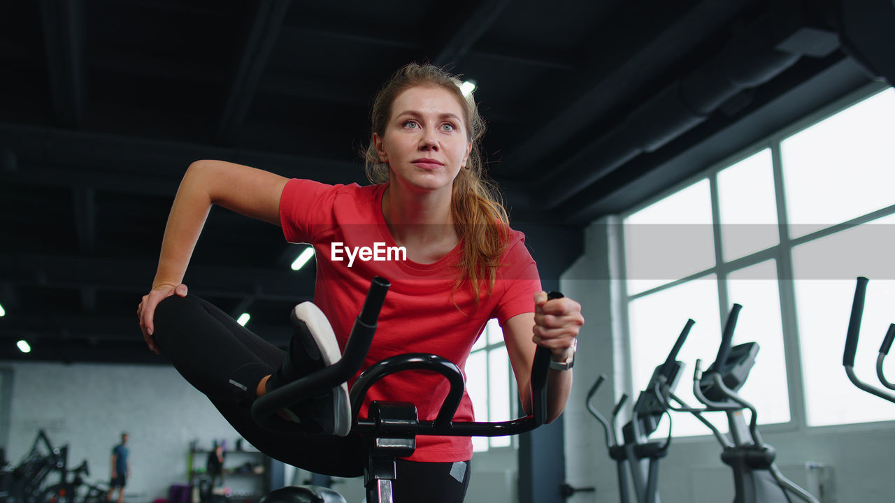 portrait of young woman sitting on wheelchair in gym