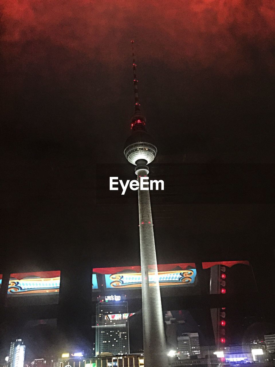 LOW ANGLE VIEW OF ILLUMINATED TOWER AGAINST SKY AT NIGHT