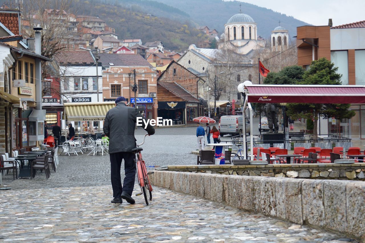 Man with bicycle walking on footpath in town