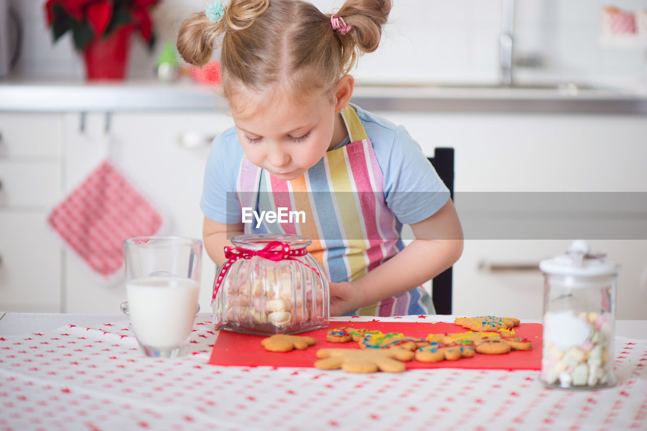 Close-up of cute girl sitting at kitchen