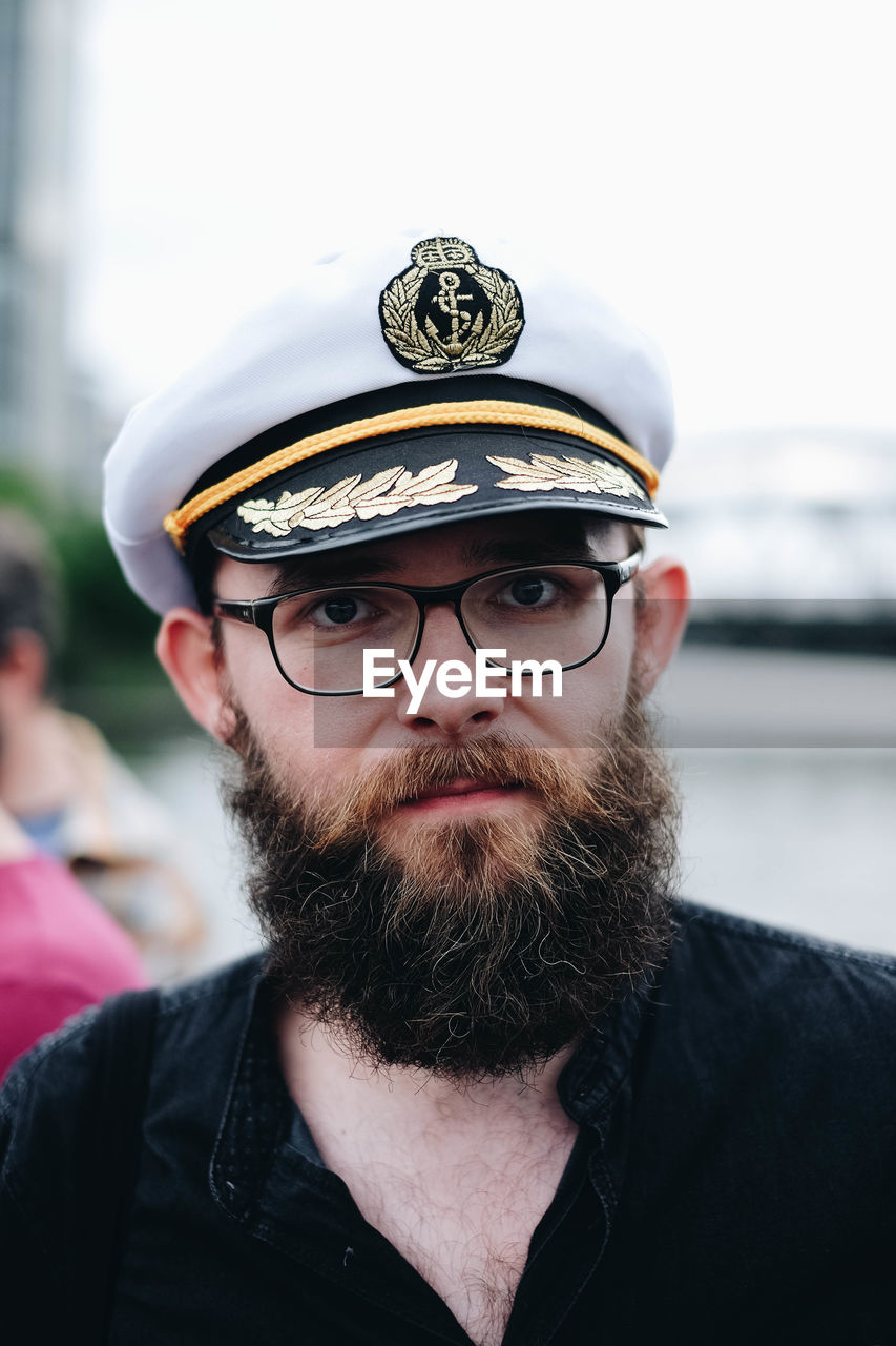 Portrait of bearded man wearing eyeglasses and cap in city