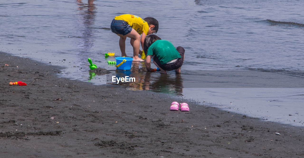 BOY PLAYING WITH TOY ON SHORE