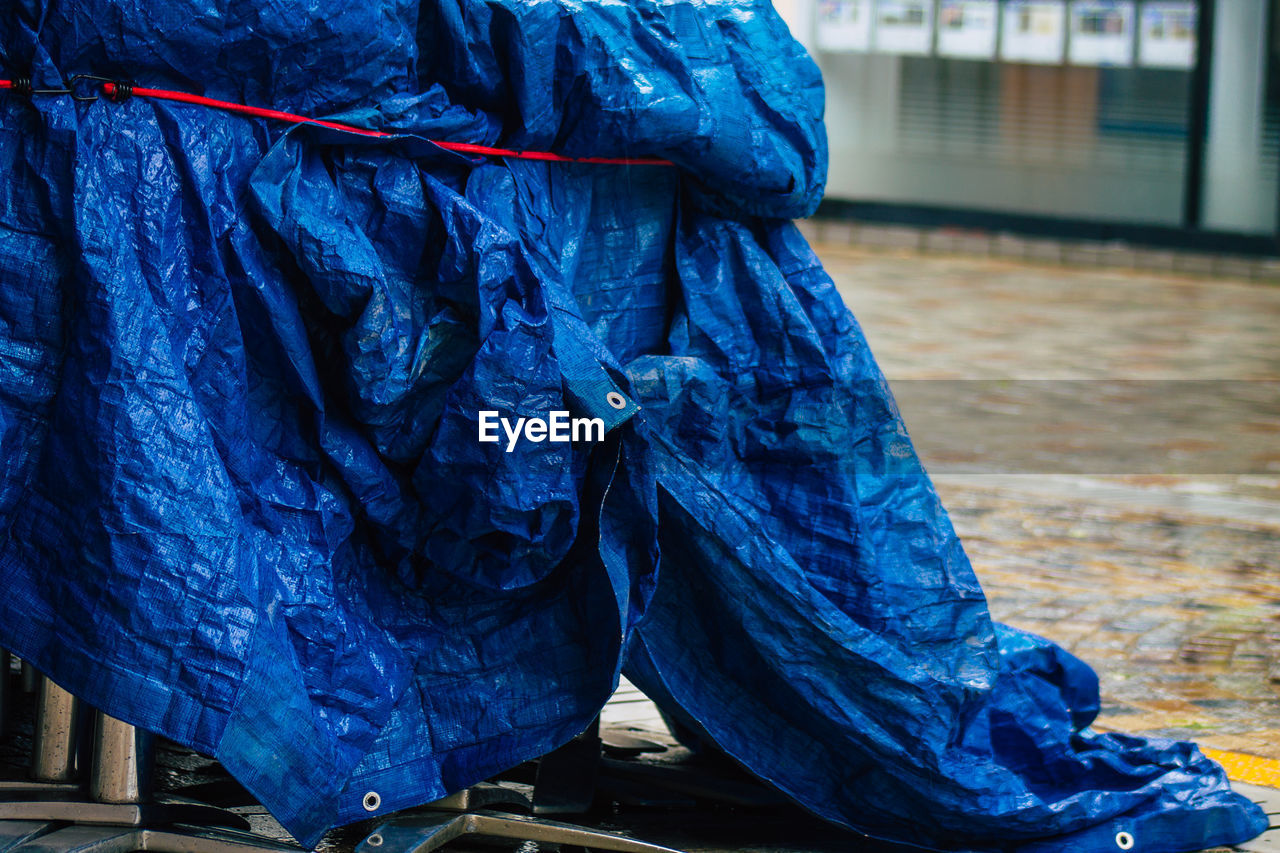 CLOSE-UP OF WOMAN WITH UMBRELLA STANDING ON WET FLOOR