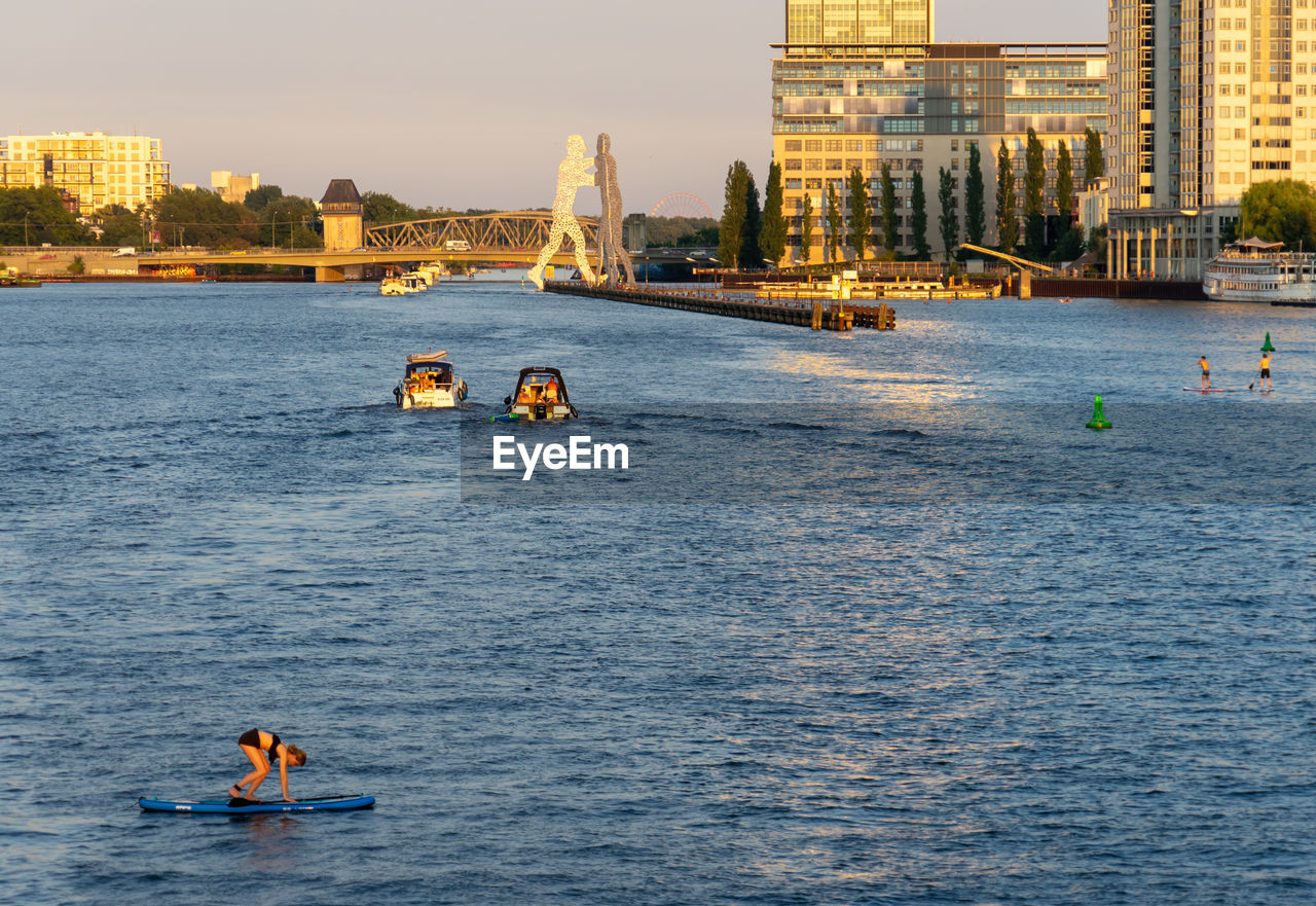 Mature woman paddleboarding on river against sky during sunset