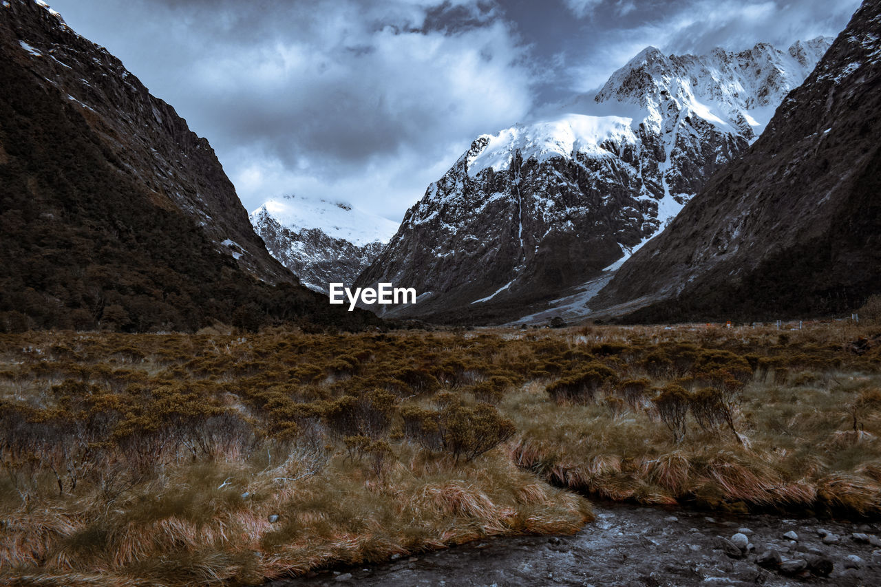 Scenic view of snowcapped mountains and glacial valley against a dramatic sky