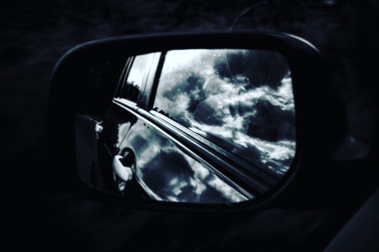 REFLECTION OF CAR ON SIDE-VIEW MIRROR AGAINST SKY SEEN THROUGH WINDOW