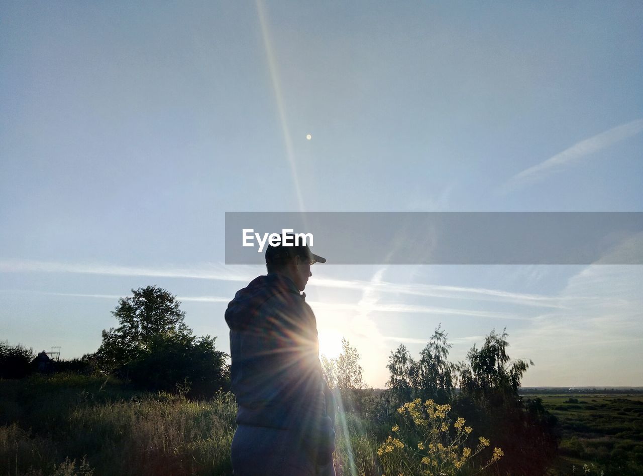 MAN ON FIELD AGAINST SKY AT SUNSET