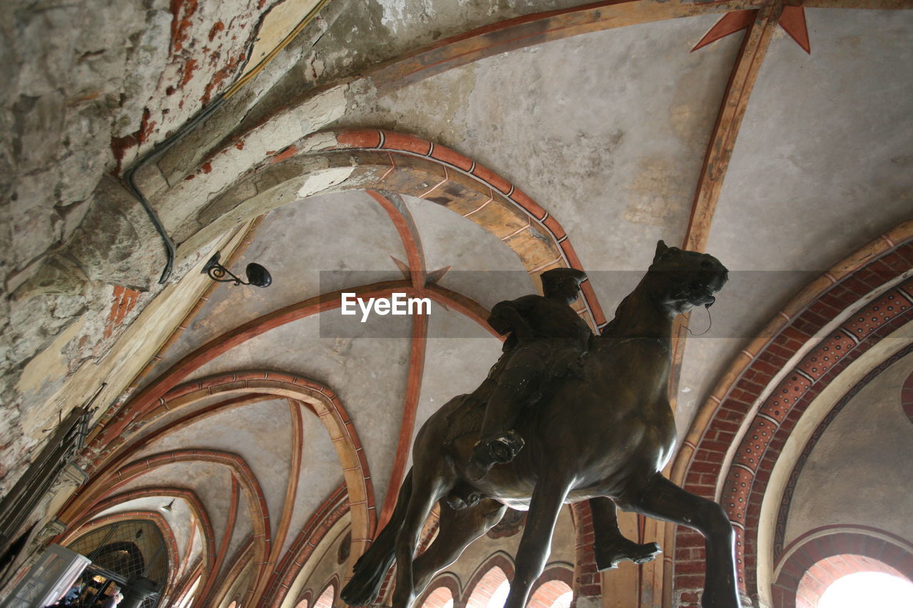 Low angle view of equestrian statue against ribbed vault ceiling in church corridor