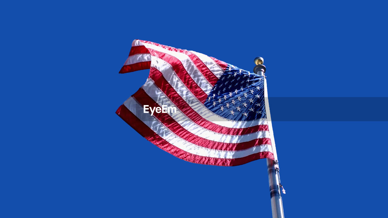 American flag unfurled and waving against a deep blue sky