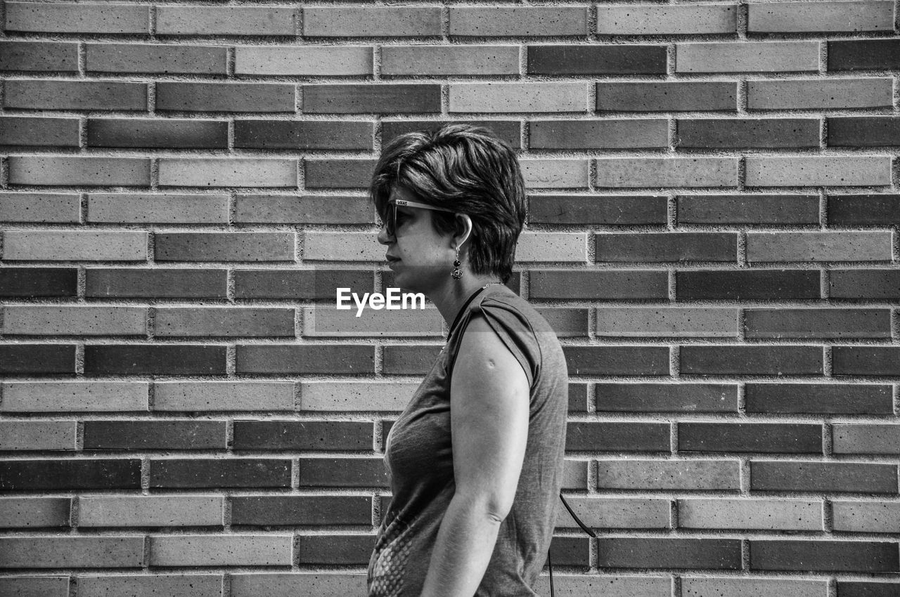 SIDE VIEW OF CHILD STANDING AGAINST BRICK WALL