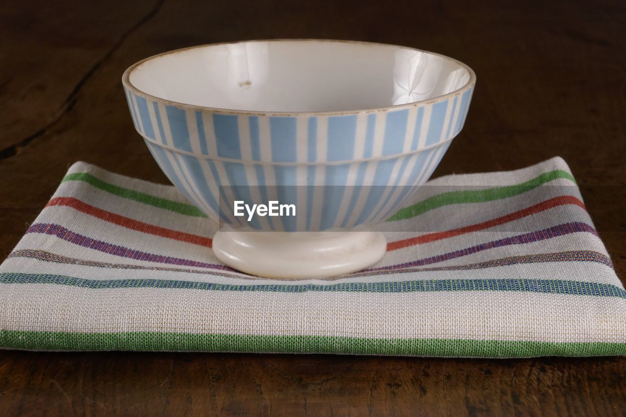 CLOSE-UP OF TEA CUP ON TABLE AGAINST WHITE BACKGROUND