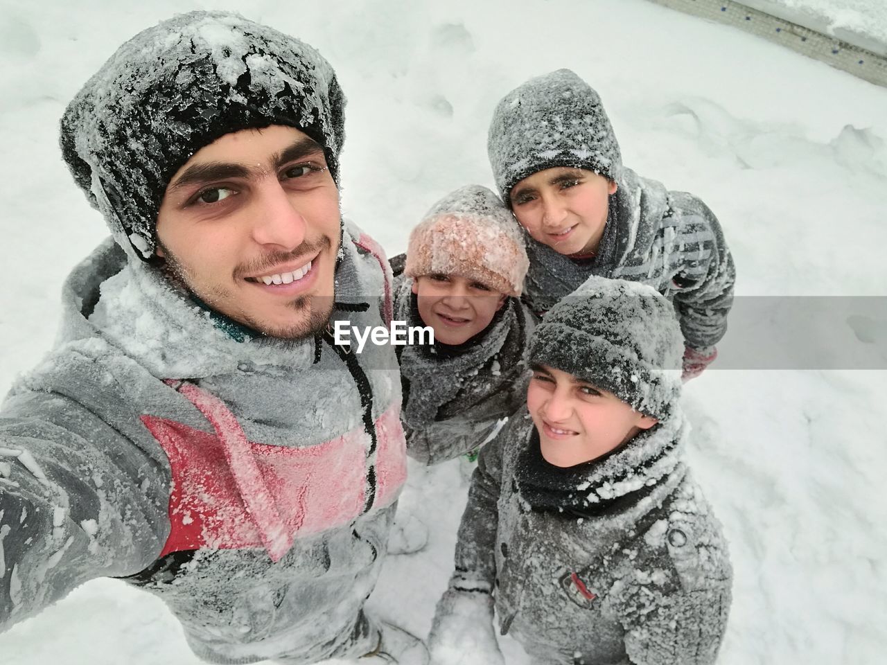 Portrait of smiling family standing on snow during winter